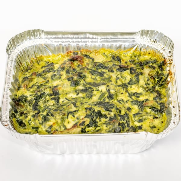 A rectangular aluminum foil pan filled with a baked spinach and cheese dish.