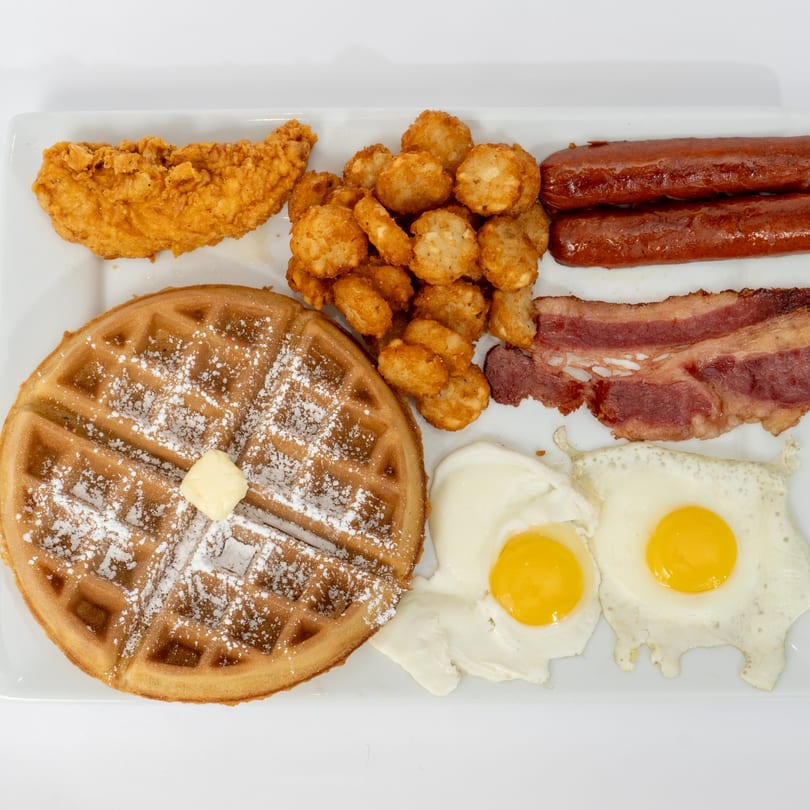 Ahsan's Halal breakfast platter with waffle, chicken, tots, sausages, bacon, and fried eggs.