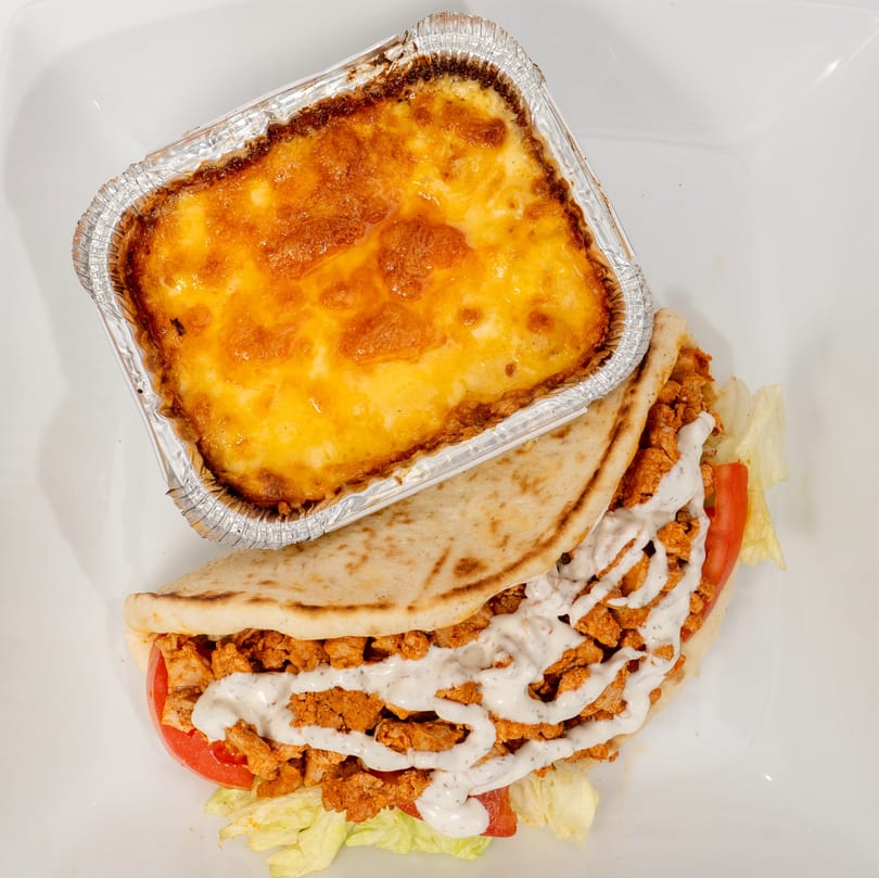 Ahsan's Halal chicken gyro with white sauce, lettuce, and tomato, next to a baked mac and cheese.