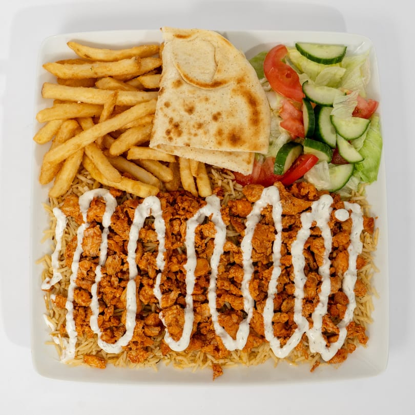 Ahsan's Halal chicken over rice, topped with white sauce, with fries, pita bread, and salad.